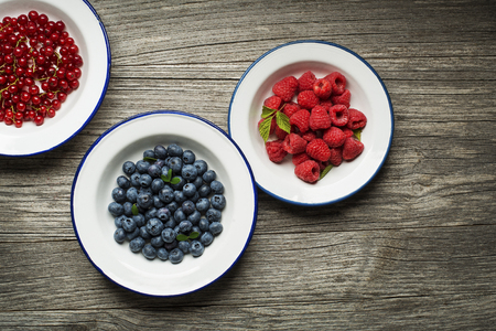 Mix of fresh berries in a bowl on wooden backgroundの写真素材