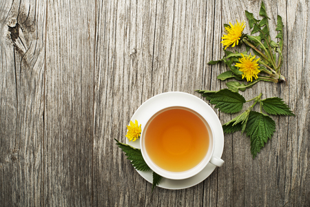 Cup of healthy herbal tea with dandelion and nettle on wooden background. Herbal medicineの写真素材