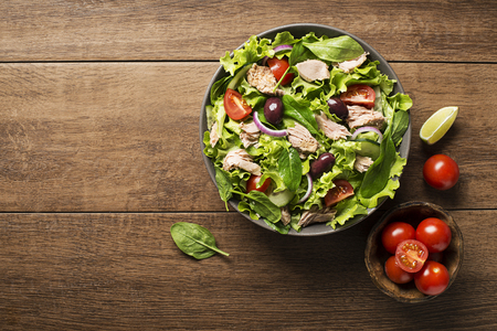 Tuna salad with lettuce, tomatoes and olives on wooden tableの写真素材