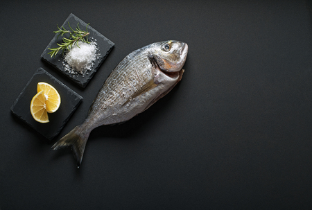 Delicious fresh gilt-head fish on dark vintage background. Healthy food diet or cooking conceptの写真素材