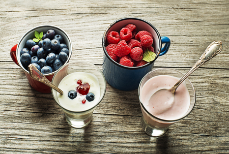 Bowl of fresh mixed berries and yogurt with fresh blueberries, raspberries served on a wooden tableの写真素材