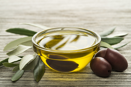Olive oil with black olives on wooden backgroundの写真素材
