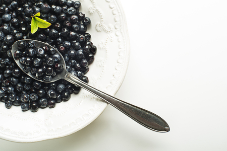 Fresh blueberries served in plate with spoon on white backgroundの写真素材
