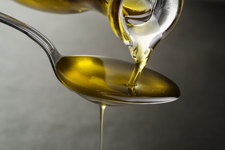 Oil pouring and dripping to the spoon close upの写真素材