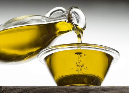 Bottle pouring olive oil in a bowl close upの写真素材