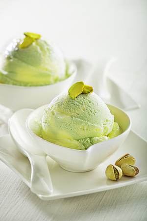 A scoop of pistachio ice cream with pistachios on white backgroundの写真素材