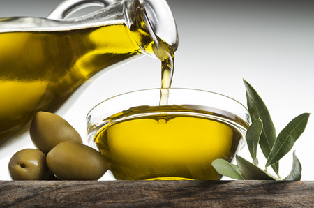 Bottle of virgin olive oil pouring in a bowl close upの写真素材