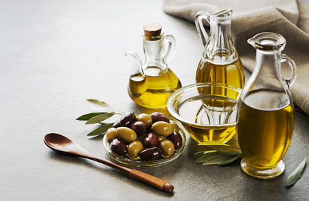Bottles of Extra virgin healthy Olive oil with fresh olives on gray backgroundの写真素材