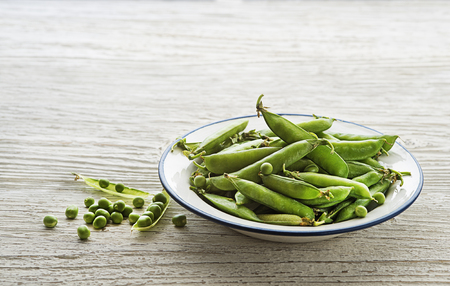 Fresh green peas in a bowl on wooden backgroundの写真素材