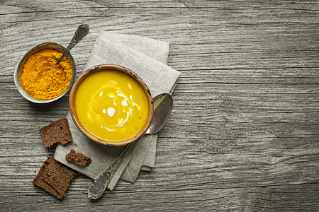 Healthy turmeric or curcuma cream soup on wooden backgroundの写真素材