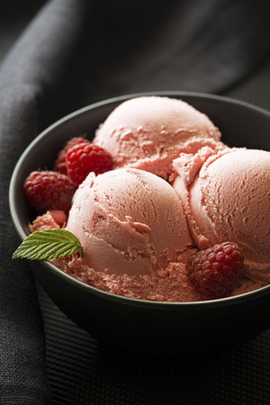Homemade organic Raspberry ice cream scoops in black bowlの写真素材