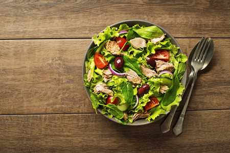 Tuna salad with lettuce, tomatoes and olives on wooden tableの写真素材