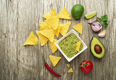 Guacamole sauce with fresh ingredients and corn nachos chips on wooden backgroundの写真素材