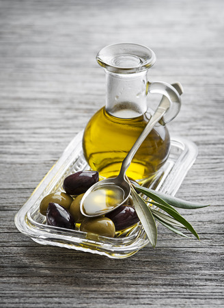 Bottle of Extra virgin healthy Olive oil with fresh olives and spoon close upの写真素材