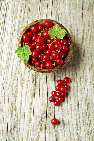 Fresh red currant berries with leaves on wooden background close upの写真素材
