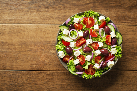 Salad with feta cheese and fresh vegetables on wooden background. Greek salad.の写真素材