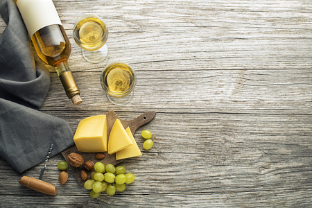 Bottle of white wine with snack food on old board. Glass of wine and cork. Wine bottle mockup. Top viewの写真素材