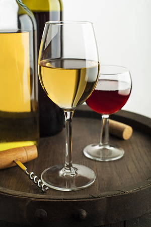 Glass and bottle of red wine and white wine on wooden barrelの写真素材