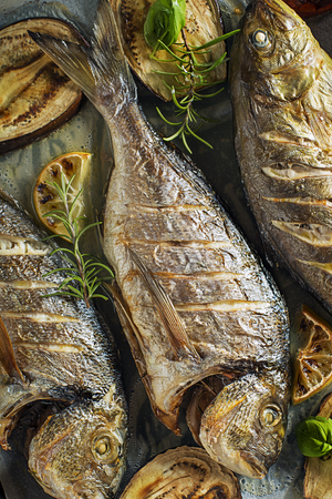 Grilled Gilt-head bream fish with vegetables and spicesの写真素材