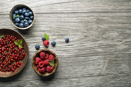 Mix of fresh berries in a bowl on wooden backgroundの写真素材