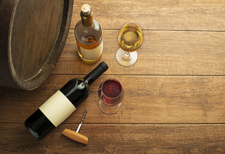 Glass and bottle of red wine and white wine with wooden barrel backgroundの写真素材