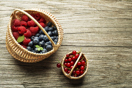 Mix of fresh berries fruit in a basket on wooden backgroundの写真素材