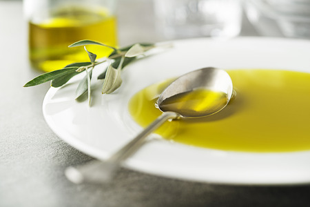 Healthy olive oil pouring with spoon close upの写真素材