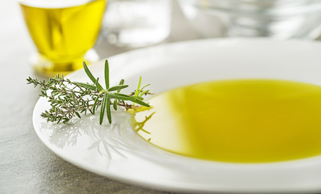 Healthy olive oil with herbs pouring in to plate close upの写真素材