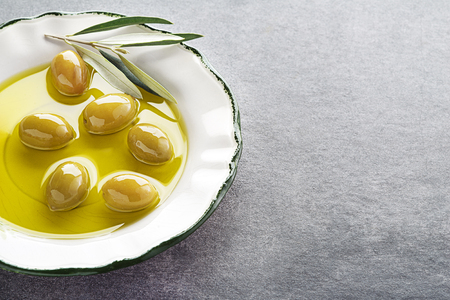 Extra virgin healthy Olive oil with fresh olives in plate close upの写真素材