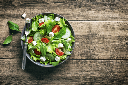 Salad with feta cheese and fresh vegetables on woodenの写真素材