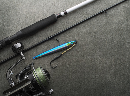 Fishing gear with rod and reel with line ready for jigging on gray background for frame, print, design - Image. Fishing tackle backgroundの写真素材