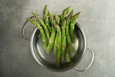 Cooking asparagus in a pot. Fresh asparagus boiled on water for cooking meal. Healthy food concept.の写真素材