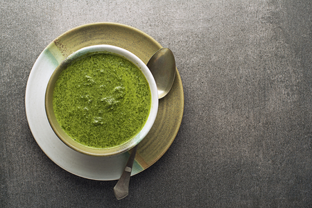 Spring healthy food. Green creamy soup with vegetables and herbs on gray backgroundの写真素材