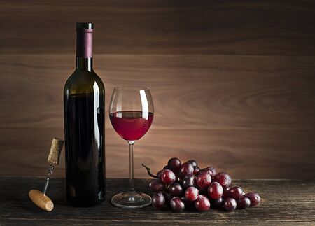 Glass and bottle of red wine on wooden backgroundの写真素材