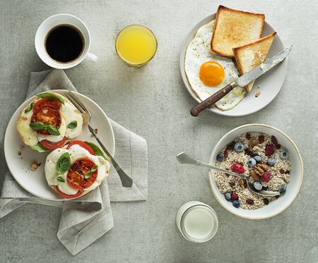 Breakfast served with oatmeal and fruits, mozzarella sandwich and fried egg with bread on table top view. Heathy breakfast food.の写真素材