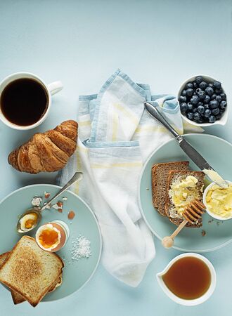 Breakfast served with coffee, croissant, egg, bread, honey and butter. Delicious healthy breakfast.の写真素材