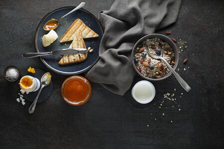 Breakfast served with oatmeal and fruits, boiled egg, jam and butter. Delicious healthy breakfast.の写真素材
