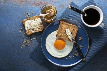 Breakfast of fried egg and bread with honey and butter on table top view. Healthy breakfast food.の写真素材
