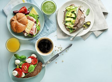 Breakfast served with different sandwiches with vegetable, cheese, ham and drinks.の写真素材