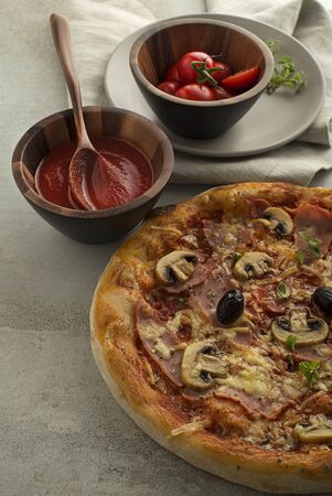 Pizza served with mozzarella cheese, ham, mushrooms and tomato sauceの写真素材