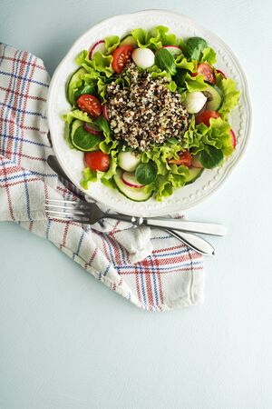 Healthy Green salad meal with fresh vegetables and quinoa seeds on blue table backgroundの写真素材
