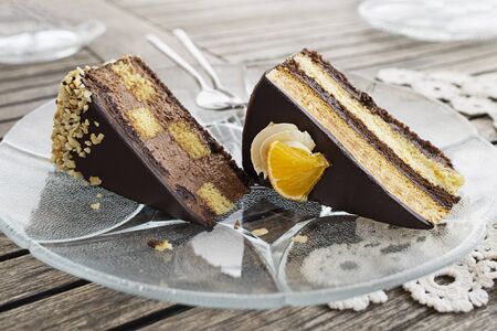 Sliced tasty chocolate cake with cream and nuts on wooden table background, closeup. Chocolate cake pieces. の写真素材
