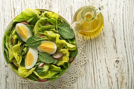 Healthy green salad with eggs on wooden table background. Healthy meal.の写真素材