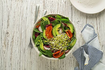 Healthy green salad meal with alfalfa sprouts, avocado and fruit on wooden backgroundの写真素材