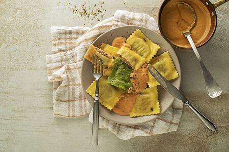 Ravioli pasta served with vegetable sauce and parmesan cheese on grey background. Small pasta envelopes containing ground meat, cheese and vegetablesの写真素材