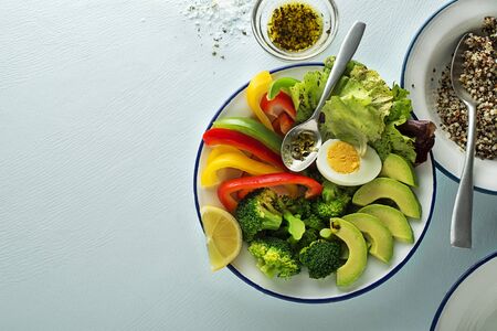 Healthy salad meal with quinoa, egg and mixed fresh vegetables on blue background top view. Food and health. Healthy meal conceptの写真素材