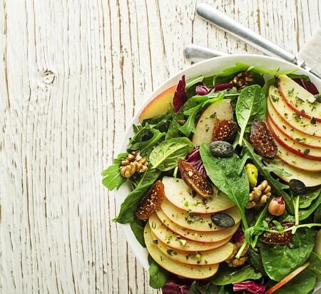 Healthy green salad with apple fruit, seeds and nuts on wooden tableの写真素材