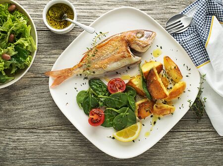 Delicious grilled fish meat with spinach and potatoes on vintage background. Healthy diet mealの写真素材