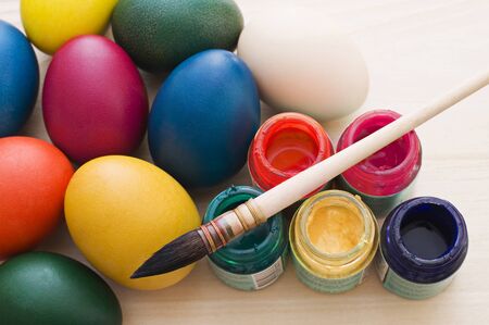 Coloring Easter eggs with a brush and paint on wooden tableの写真素材