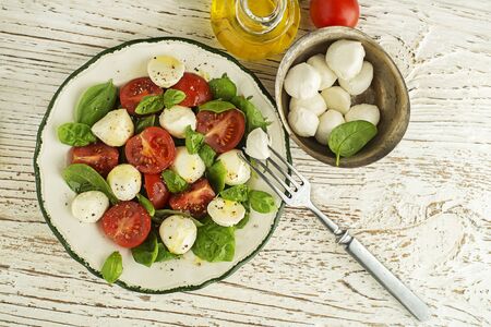 Delicious caprese salad with ripe tomatoes and mozzarella cheese with fresh basil leaves. Italian food. Salad with mozzarella, tomatoes, basil, salt, black pepper, olive oilの写真素材